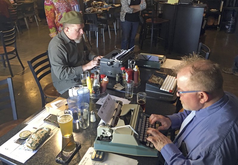 Joe Van Cleave, left, and Rich Boucher try out various vintage typewriters at an April 23 “type-in” in Albuquerque. (AP Photo/Russell Contreras)