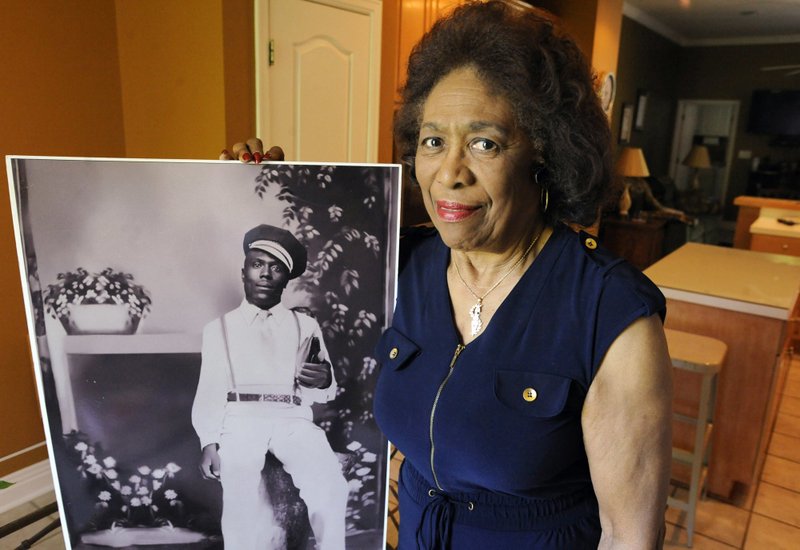 Josephine Bolling McCall poses with a photo of her father, lynching victim Elmore Bolling