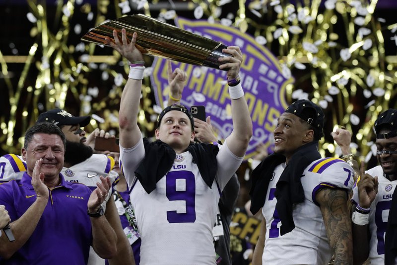 FILE - In this Monday, Jan. 13, 2020, file photo, LSU quarterback Joe Burrow holds the trophy as safety Grant Delpit looks on after LSU defeated Clemson 42-25 in the NCAA College Football Playoff national championship game, in New Orleans. Imagine if a pandemic had shortened or wiped out that last, golden season for Burrow, who won the Heisman Trophy and led LSU to the national championship. Would he still have emerged as the first overall NFL draft pick? (AP Photo/Sue Ogrocki, File)