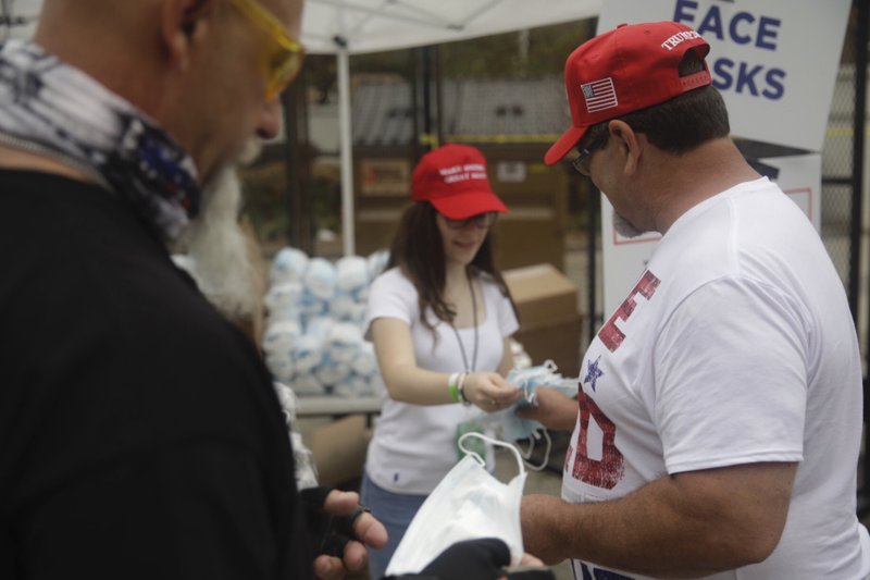 Masks to protect against COVID-19 are handed to supporters as they enter safety barricade for President Donald Trump's campaign rally on Saturday, June 20, 2020 in Tulsa, Oka. (Mike Simons/Tulsa World via AP)