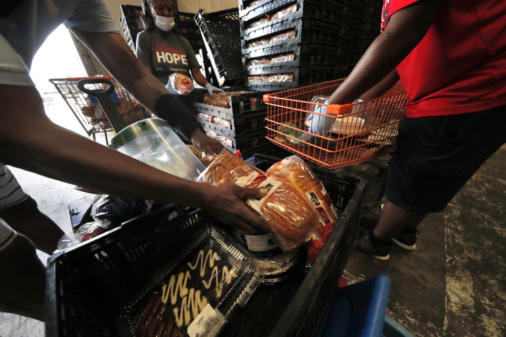 Volunteers distribute food to recipients at the Giving Hope Food Pantry during a food giveaway, which was organized by City Councilmember Cyndi Nguyen, in New Orleans, Tuesday, July 21, 2020. The effort is to assist people who have lost income during the COVID-19 pandemic. (AP Photo/Gerald Herbert)