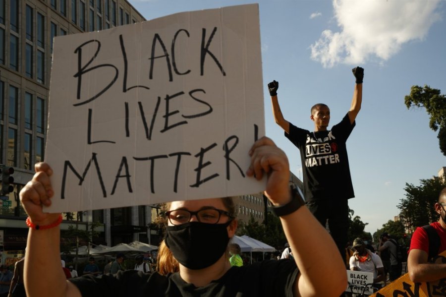 FILE - In this June 24, 2020, file photo, Antonio Mingo, right, holds his fists in the air as demonstrators protest in front of a police line on a section of 16th Street that's been renamed Black Lives Matter Plaza, in Washington. Thousands of Black activists from across the U.S. will hold the 2020 Black National Convention on Aug. 28, 2020, via livestream to produce a new political agenda that builds on the protests that followed George Floyd’s death. Organizers of the gathering shared their plans with The Associated Press on Wednesday, July 1, ahead of an official announcement. (AP Photo/Jacquelyn Martin, File)