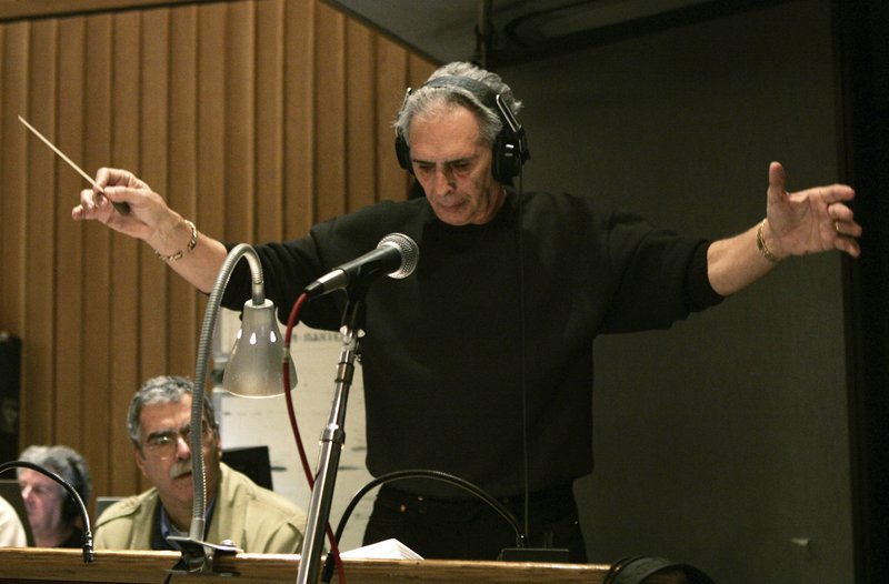FILE – In this Feb. 21, 2005, file photo, composer and conductor Bill Conti, music director of the 77th Academy Awards, conducts the show's orchestra during a rehearsal at Capitol Recording Studios in Los Angeles. Conti, the Oscar- and Emmy Award-winning composer who wrote scores for movies including “Rocky,” “The Right Stuff” and “The Karate Kid” is giving them to Louisiana State University. Conti, who grew up in Miami, went to LSU on a bassoon scholarship. The William and Shelby Conti Papers are expected to arrive sometime in the fall. (AP Photo/Kevork Djansezian, File)