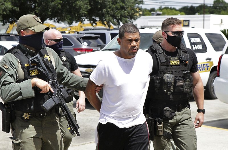 Neil Broussard, escorted by law enforcement, is brought into the Calcasieu Parish Sheriff’s Office Thursday morning, July 16, 2020, in Lake Charles, La. Workers at a Dollar General store recognized Broussard, a convicted sex offender accused of killing two teenagers and kidnapping a third, and locked him in after quietly escorting other customers out. (Donna Price/The Daily Advertiser via AP)/American Press via AP)