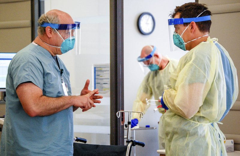 Dr. Michael Saag, left, speaks with an unidentified coworker in Birmingham, Ala., on Friday, July 10, 2020. Saag survived COVID-19 and now treats patients with the disease. (Amanda Chambers/University of Alabama at Birmingham via AP)