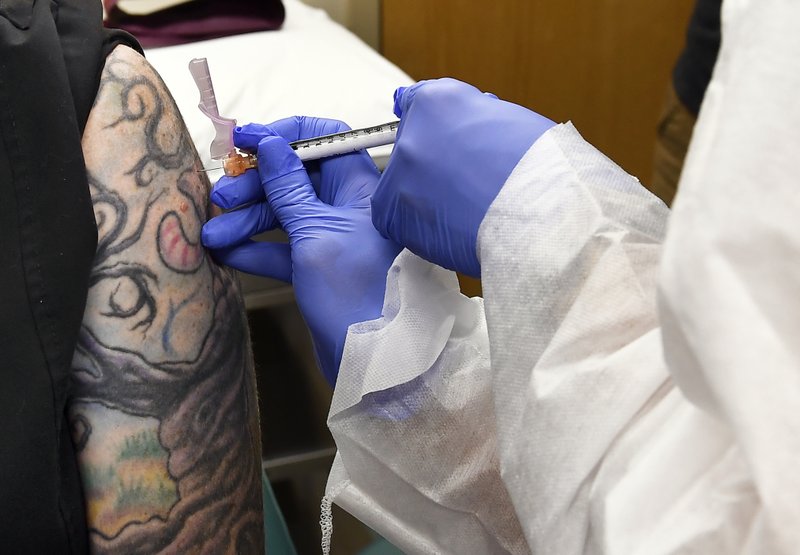 FILE - In this July 27, 2020, file photo, Nurse Kathe Olmstead, right, gives volunteer Melissa Harting, of Harpersville, N.Y., an injection as a study of a possible COVID-19 vaccine, developed by the National Institutes of Health and Moderna Inc., gets underway in Binghamton, N.Y. A letter from federal health officials instructing states to be ready to begin distributing a vaccine by Nov. 1 — two days before the election — has met, not with exhilaration, but with suspicion among public health experts and others. (AP Photo/Hans Pennink, File)