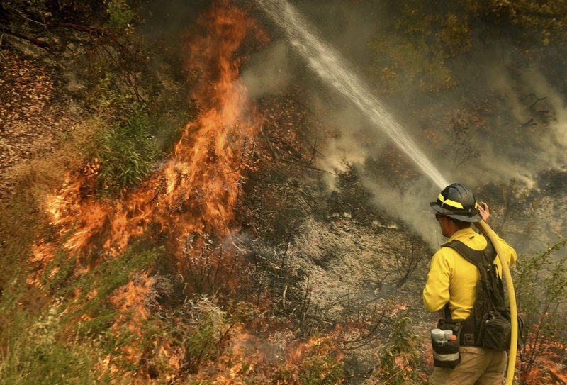 A firefighter puts out a hot spot along Highway 38 northwest of Forrest Falls, Calif., as the El Dorado Fire continues to burn Thursday afternoon, Sept. 10, 2020. The fire started by a device at a gender reveal party on Saturday. (Will Lester/The Orange County Register/SCNG via AP)