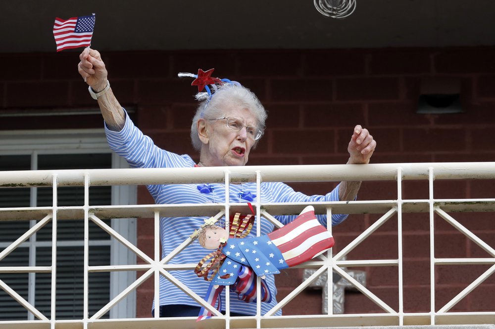 A resident of the Lambeth House, where a cluster of the coronavirus has formed, reacts from her balcony as opera singers Irini Hymel and Bryan Hymel sing to the quarantined residents in New Orleans, Friday, March 20, 2020. (AP Photo/Gerald Herbert)