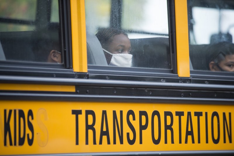 Students arrive by bus at Foundation Preparatory School for their return to school during the coronavirus in New Orleans on Monday, Oct. 12, 2020. It was the first day of in-person learning for fifth-12th grade public school students in Orleans Parish. (Chris Granger/The Times-Picayune/The New Orleans Advocate via AP)