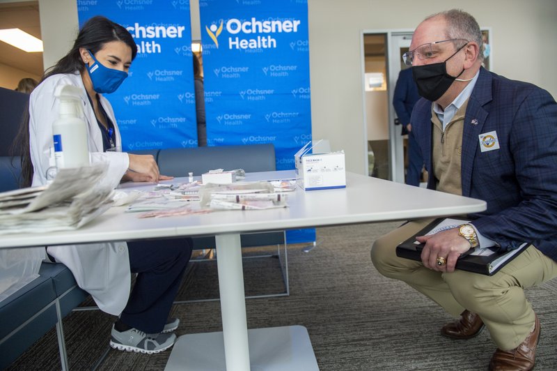 Louisiana Governor John Bel Edwards, right, talks with Dr. Mona Moghareh, a pharmacist with Ochsner Medical Center in Jefferson, La., as she sets up a station to administer the first vials of the coronavirus vaccine on Monday, Dec. 14, 2020. (Chris Granger/The Advocate via AP)
