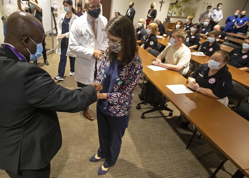 Father Don Ajoko, Phd. anoints the hands of Dr. Catherine O'Neal of Our Lady of the Lake Regional Medical Center, along with members of the nearly three dozen healthcare workers from around the country who arrived to help supplement the staff at the Medical Center in Baton Rouge, La., Monday, Aug. 2, 2021. Louisiana has one of the lowest coronavirus vaccination rates in the nation and is seeing one of the country’s worst COVID-19 spikes. (AP Photo/Ted Jackson)